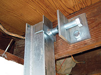 Securing the i-beam system to the top of the floor joist in a foundation wall repair in Wisconsin Rapids.